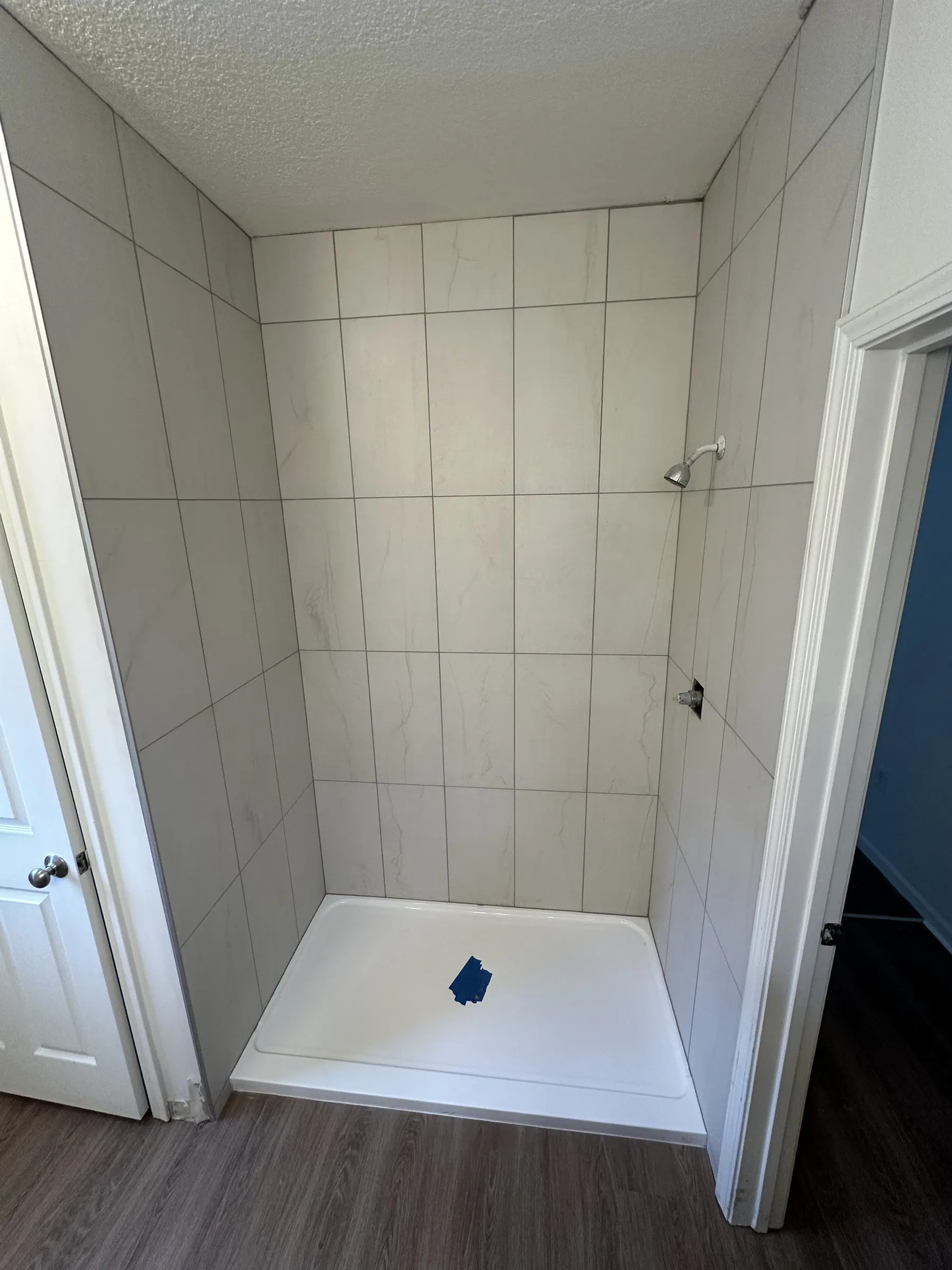 A white tile shower on a new base, where a tub used to be