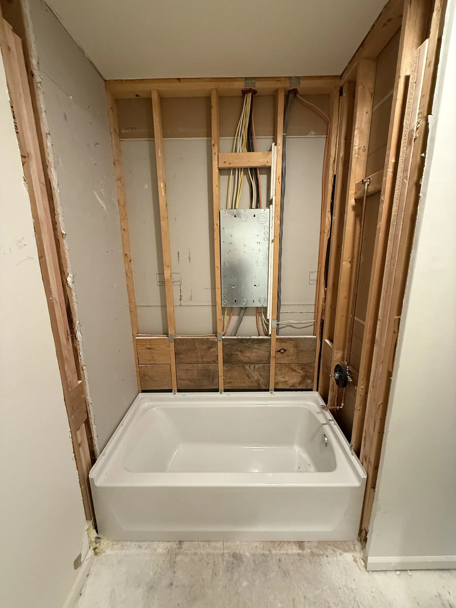 A tub alcove opened to the studs with the new tub set, before the waterproofing goes on